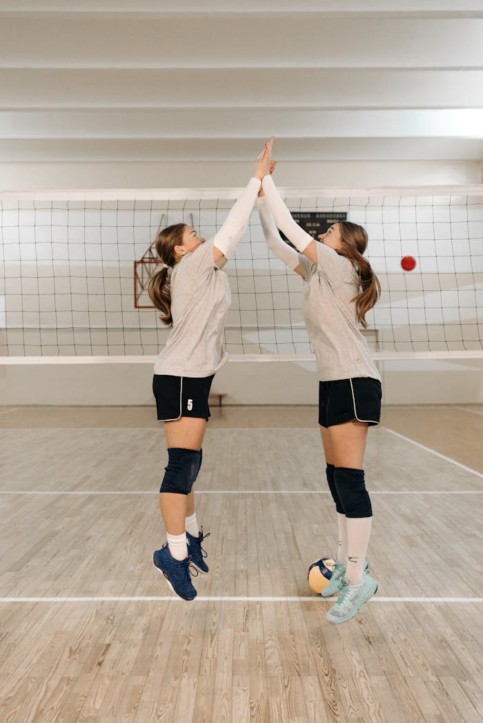 Two female volleyball players practicing indoors, showcasing teamwork in action during a training session.